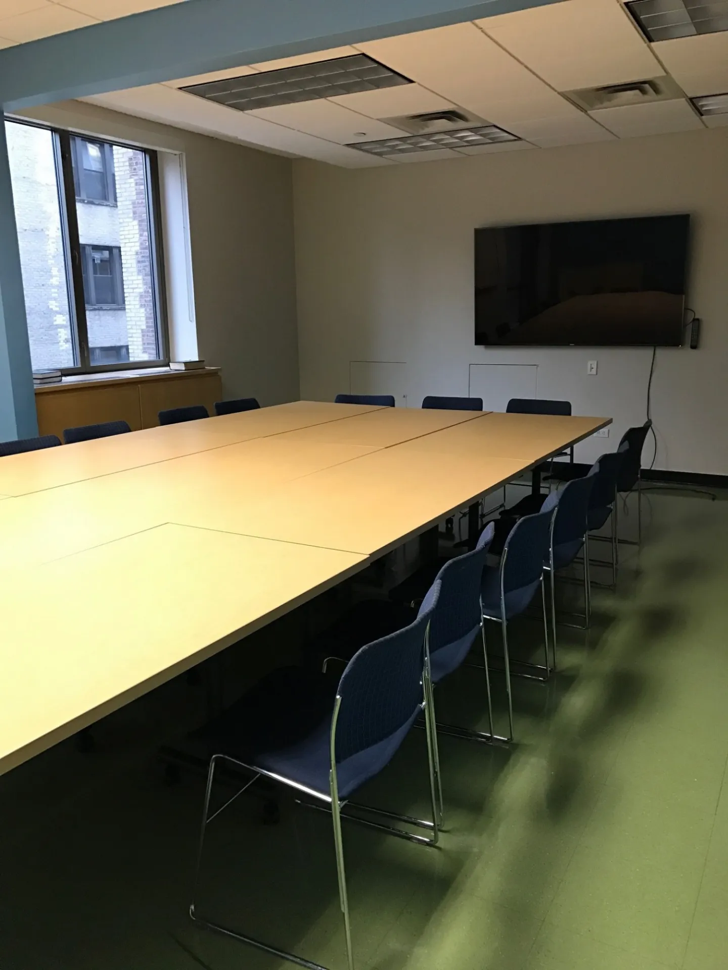 Long table, moveable chairs, monitor on the wall